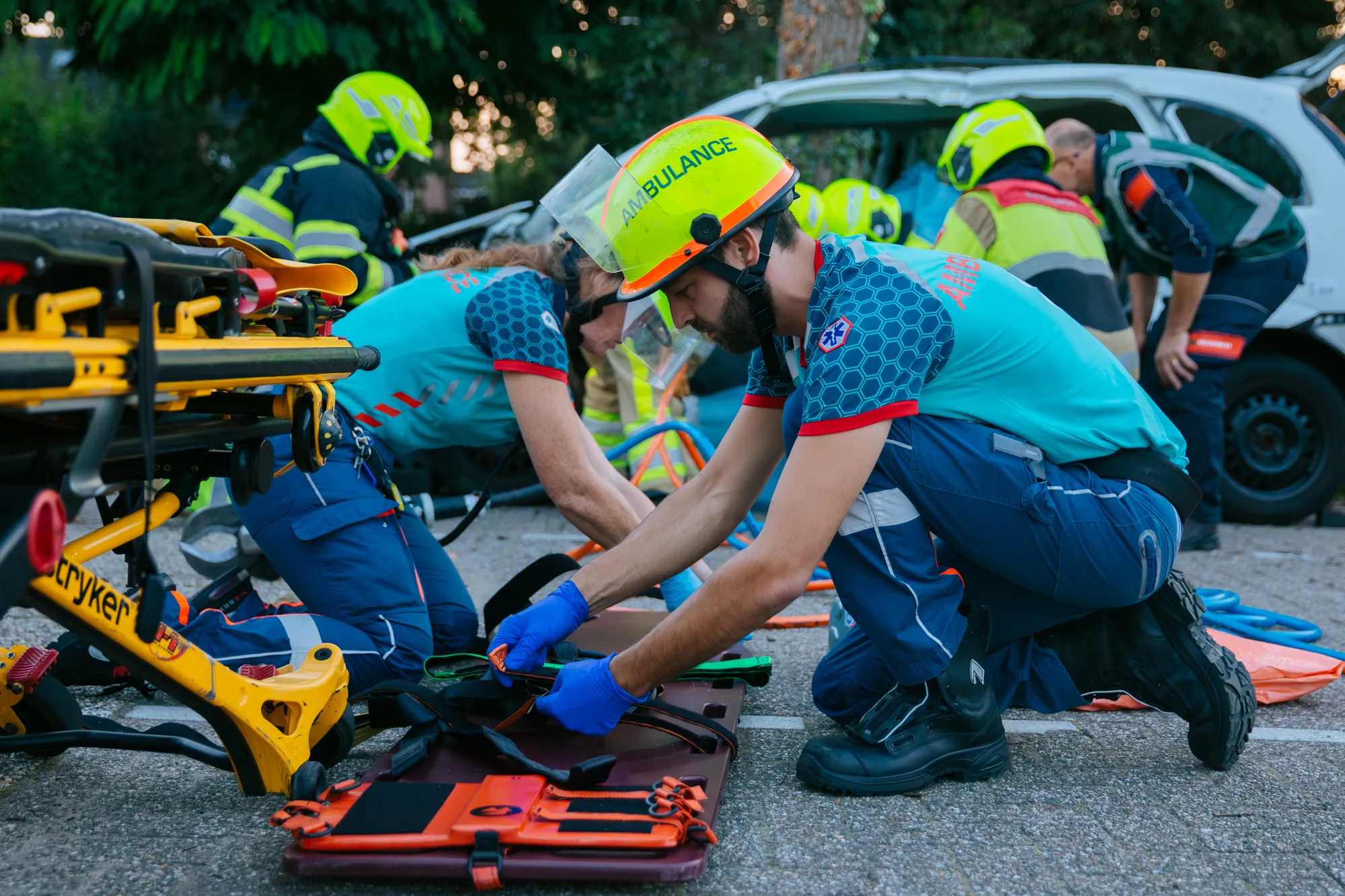 Twee ambulanceverpleegkundigen verlenen langs de weg zorg aan een slachtoffer.